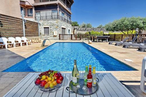 a table with a bowl of fruit next to a swimming pool at הרמוניה בכפר - וילה מקסימה עם בריכה פרטית מחוממת וג'קוזי in ‘Ein el Asad