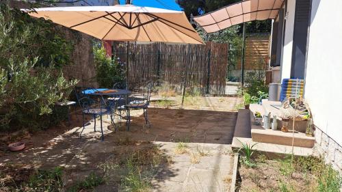 een patio met een parasol en een tafel en stoelen bij chambre d'hôte chez l'habitant in Sète