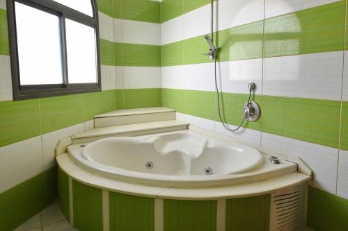 baño verde y blanco con bañera en הרמוניה בכפר - וילה מהממת וגדולה עם ממ"ד, בריכה מחוממת וג'קוזי בגליל en ‘Ein el Asad