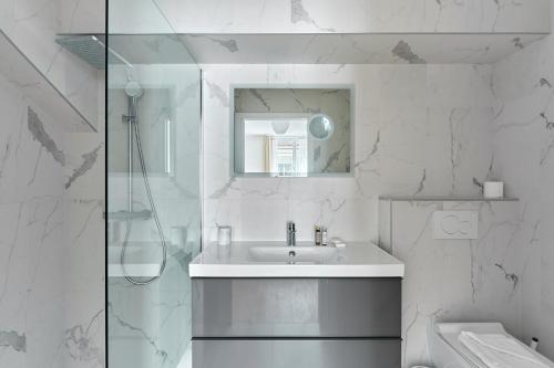 een witte badkamer met een wastafel en een douche bij Résidence Porte Maillot Arc de triomphe by Studio prestige in Parijs