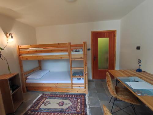 Zimmer mit einem Schreibtisch, einem Etagenbett und einem Tisch in der Unterkunft Vivere in un bosco Casa Leonardo in Villar Perosa
