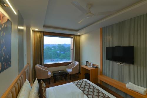 a hotel room with a bed and a window at Hotel Swagat Suites in Haridwār