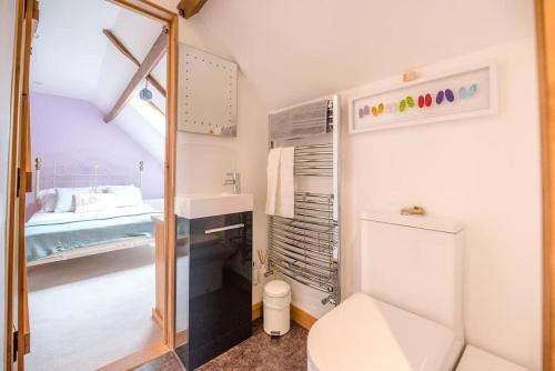 a bathroom with a toilet and a sink and a bed at The Old Coach House, Leiston in Leiston