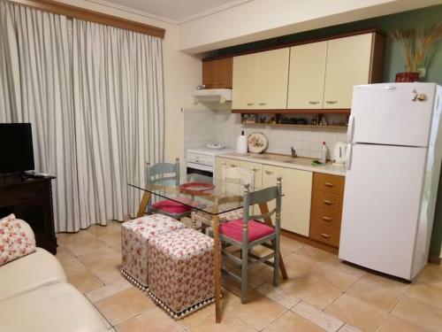 a kitchen with a table and a white refrigerator at Παραθαλάσσιο διαμέρισμα με κήπο στον Αγιόκαμπο in Agiokampos