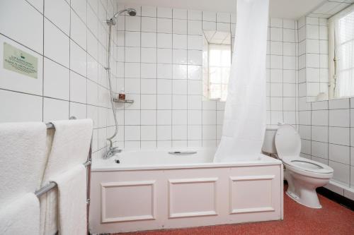a white bathroom with a tub and a toilet at Bridge Inn by Greene King Inns in Port Sunlight