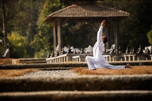 a man doing a yoga pose in front of a gazebo at Dwarika's Sanctuary in Dhulikhel