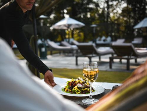a person reaching for a plate of food and a glass of wine at Dwarika's Sanctuary in Dhulikhel