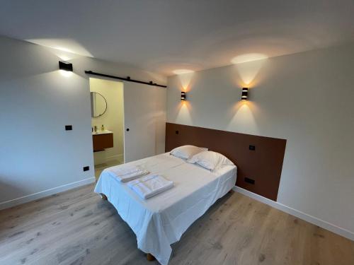 - une chambre avec un lit doté de draps blancs et d'un miroir dans l'établissement Les Clapotis chambres pieds dans l eau lac d Annecy, à Angon