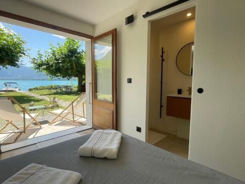 - une chambre avec un lit et une vue sur l'océan dans l'établissement Les Clapotis chambres pieds dans l eau lac d Annecy, à Angon