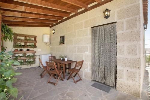 a patio with a table and chairs and a wall at Las Tres Palmeras in Güimar