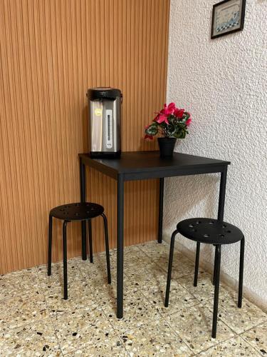 a table with a coffee maker on it with two stools at Breezot Yam in Nahariyya