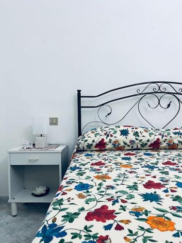 マリーナ・ディ・マンカヴェルサにあるCasa vacanzeの花柄の掛け布団とナイトスタンド付きのベッド