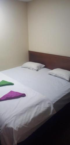 1 cama blanca con 2 almohadas y toallas en Q one hotel, en Kampung Dengkil