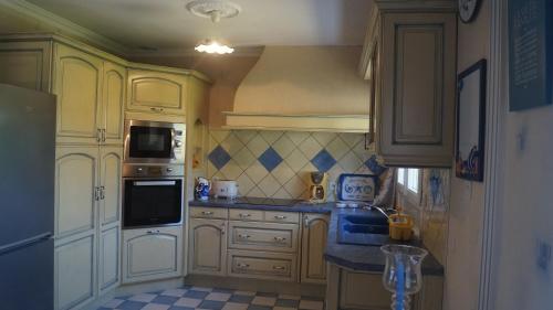 Il comprend une cuisine avec des placards blancs et du carrelage bleu. dans l'établissement La Loumas, à Chargé