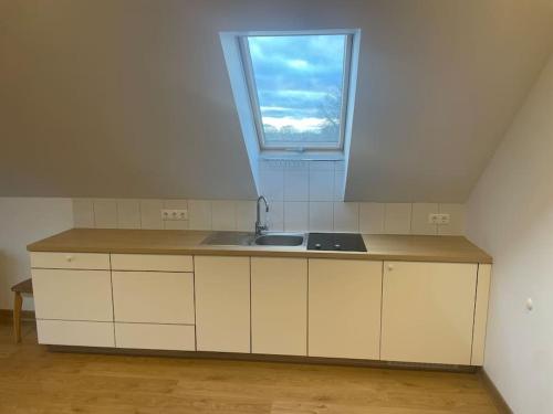 an attic kitchen with a sink and a window at Comfortable apartments - Nature, silence, coziness in Kėdainiai