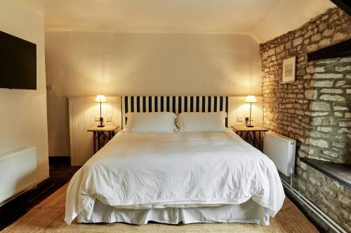 a bedroom with a large white bed with two lamps at The Sherborne Arms in Northleach