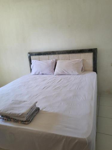 een wit bed met witte lakens en kussens bij Anno Guest House in Makassar