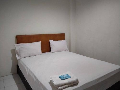 1 dormitorio con 1 cama blanca y 2 toallas en Anno Guest House en Makassar