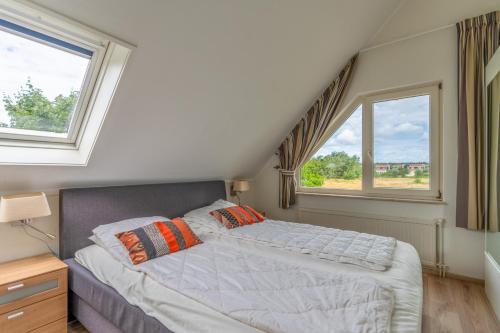1 dormitorio con 1 cama y 2 ventanas en Villapark Kamperfoelie 69, en De Koog
