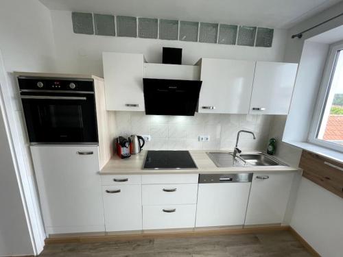 a kitchen with white cabinets and a black appliance at Homestay - Luxus Ferienwohnung in Bad Griesbach