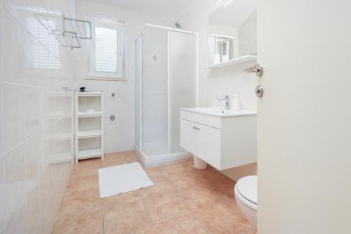 a white bathroom with a toilet and a sink at Sea view by Moro 3 in Malinska