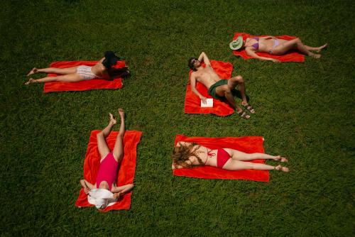 a group of people laying on red blankets on the grass at Lopota Lake Resort & Spa in Napareuli
