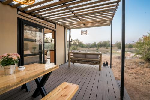 a wooden deck with a bench and a table at Kamoka Camp in Hoedspruit