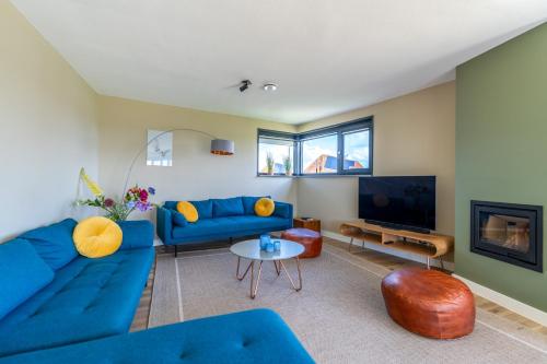 a living room with blue couches and a tv at Natuurvilla 14 Westerkolk in De Waal