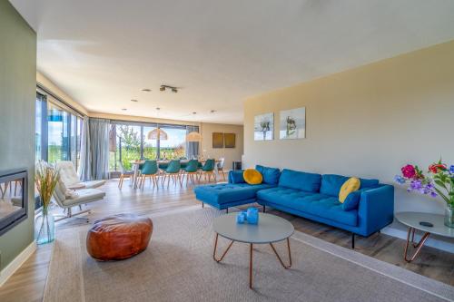 a living room with a blue couch and chairs at Natuurvilla 14 Westerkolk in De Waal