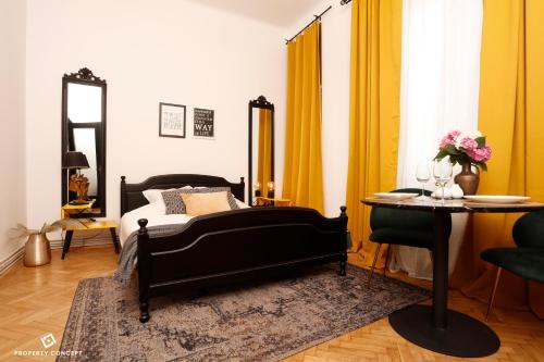 um quarto com uma cama, uma mesa e cortinas amarelas em Bohemian Central Concept Studio em Bucareste