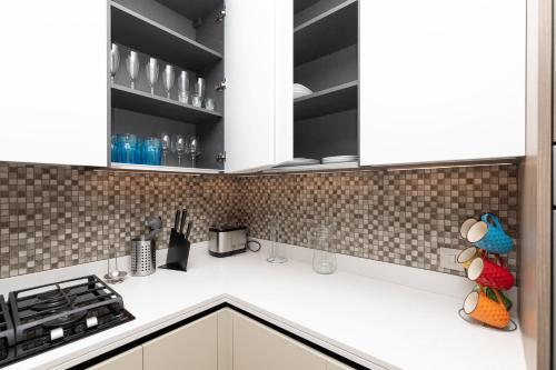 a kitchen with white cabinets and white counter tops at LUXURY 1 BR Apartment at Marina Gate Jumeirah Living in Dubai