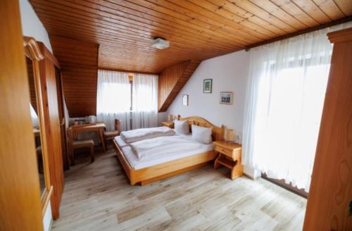 ein Schlafzimmer mit einem großen Bett und einer Holzdecke in der Unterkunft Drexl Gasthof Shiro in Schondorf am Ammersee