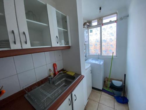 eine kleine Küche mit einem Waschbecken und einem Fenster in der Unterkunft Departamento familiar in Curicó
