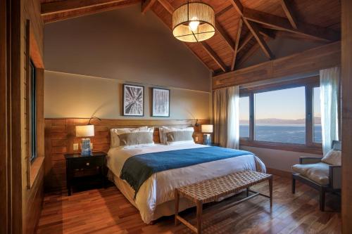 a bedroom with a large bed and a large window at Los Cauquenes Resort + Spa + Experiences in Ushuaia