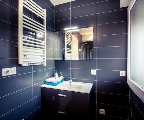 une salle de bain avec un lavabo et un miroir dans l'établissement Golden Beach parking proche du lac, à Annecy