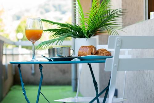 une table avec un verre de jus d'orange et une assiette de pain dans l'établissement Golden Beach parking proche du lac, à Annecy