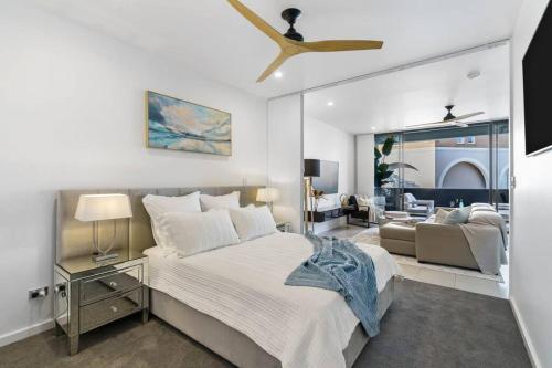 a white bedroom with a bed and a couch at Elegance on Pine - by Coast Hosting in Terrigal