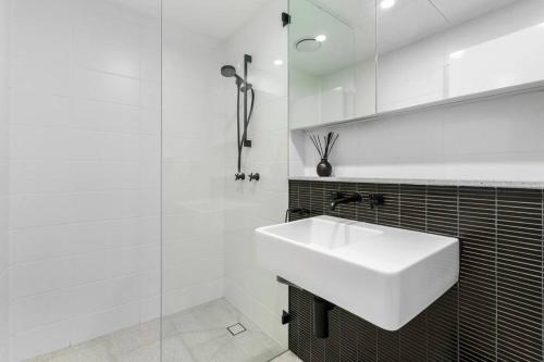 een witte badkamer met een wastafel en een douche bij Elegance on Pine - by Coast Hosting in Terrigal