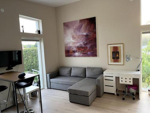uma sala de estar com um sofá e uma secretária em Nybyggt gästhus nära havet och Göteborg em Kullavik