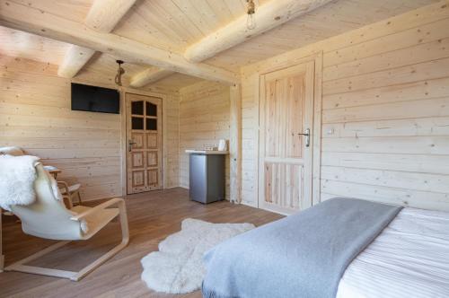 a bedroom with wooden walls and a bed and a chair at Dom Tatrzański Ewa II in Kościelisko