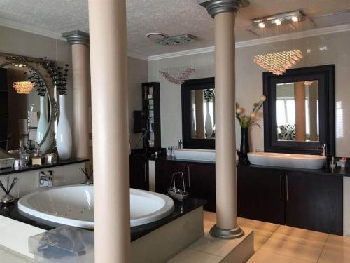 a bathroom with a large tub and two mirrors at Sleep Haven in Johannesburg
