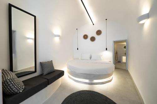 Habitación blanca con cama y espejo en Bligos Villas, en Oia