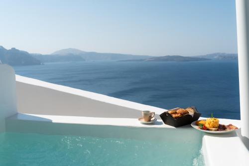 a plate of food and a bowl of food on the edge of a boat at Bligos Villas in Oia