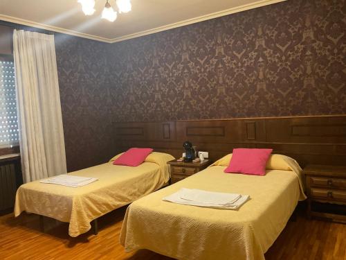 een kamer met 2 bedden en roze kussens bij La Chalana in Pola de Laviana