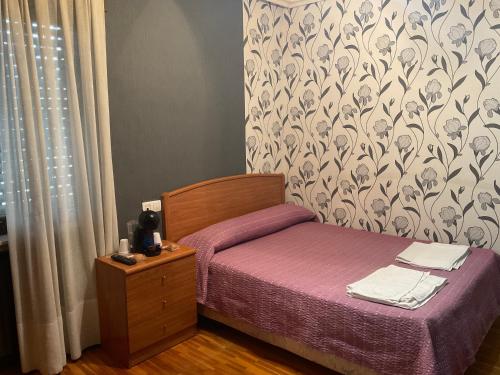 a small bedroom with a small bed with purple sheets at La Chalana in Pola de Laviana