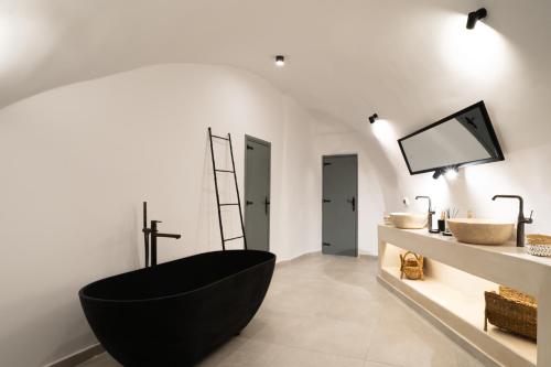 a bathroom with a black tub and a sink at Bligos Villas in Oia