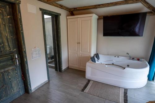 a bathroom with a tub and a tv on the wall at Bârlogul Vikingilor in Şotrile