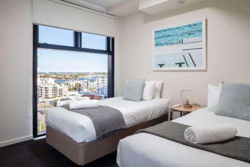 two beds in a room with a large window at First Light Mooloolaba, Ascend Hotel Collection in Mooloolaba