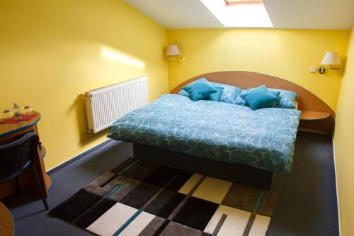 a bedroom with a bed with blue pillows on it at Restaurace-Penzion U Pilota in Kněževes