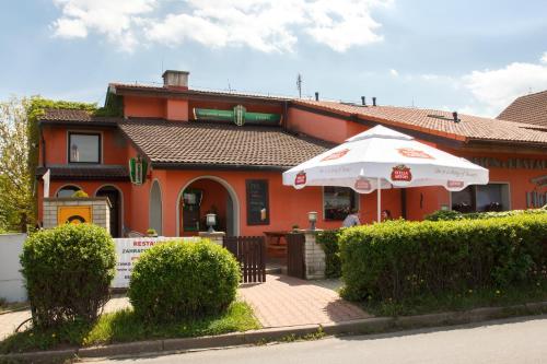 a orange building with an umbrella in front of it at Restaurace-Penzion U Pilota in Kněževes